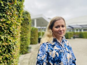 Kvinna står vid buske. Leila McDougal, manusförfattare, producent och skådespelare i Filmen Just a Farmer. 