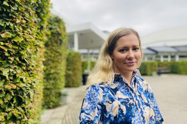 Kvinna står vid buske. Leila McDougal, manusförfattare, producent och skådespelare i Filmen Just a Farmer.
